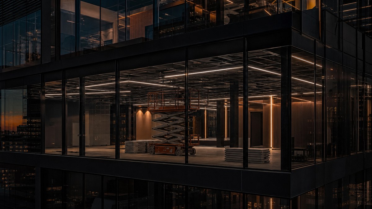 Commercial LED light installation in a Fort Worth office building with a lift and new linear LED fixtures at dusk